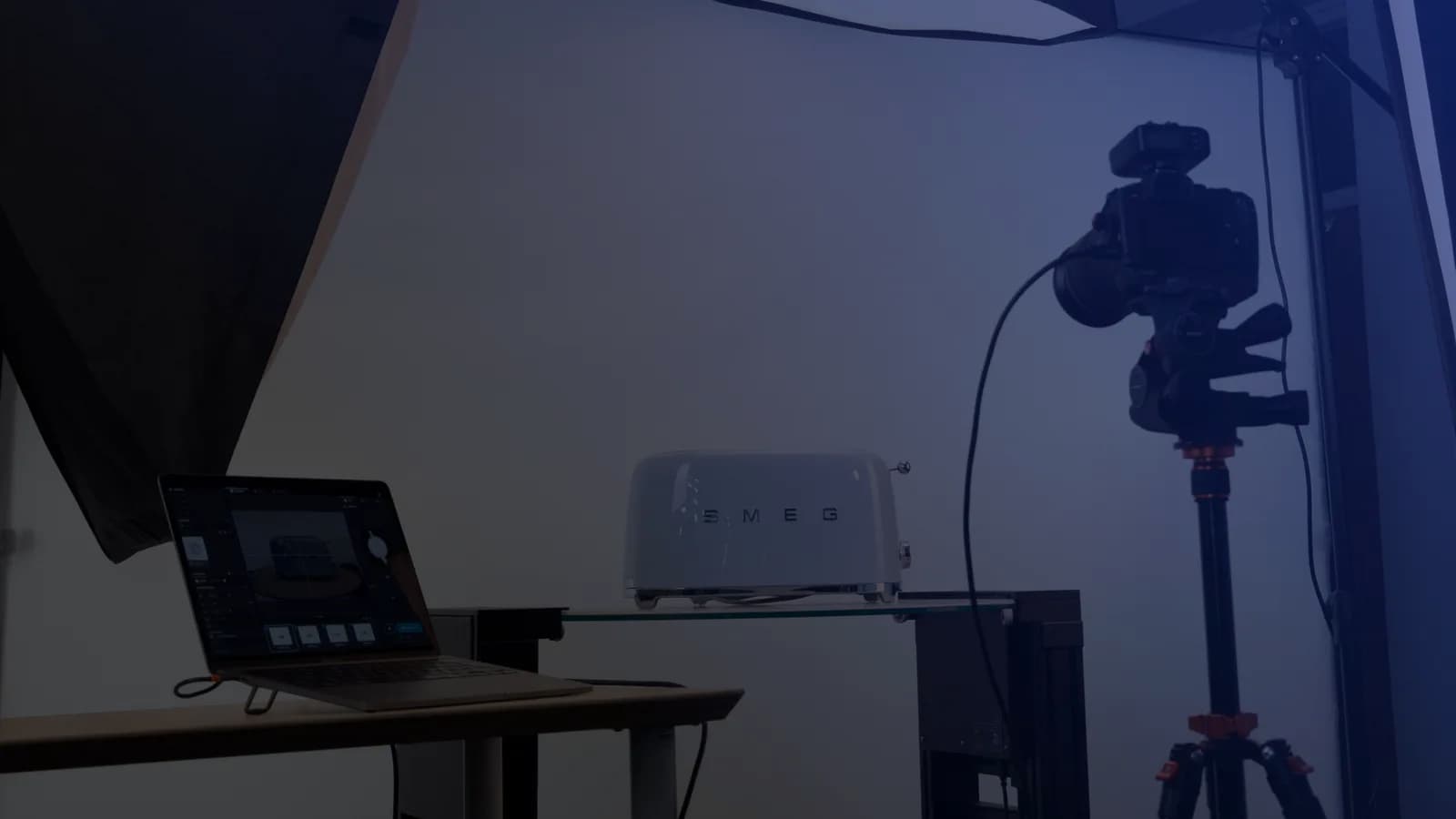 Tethered produktfotografering - en laptop med optagesoftware ved siden af et kamera på stativ og et produkt på en glashylde