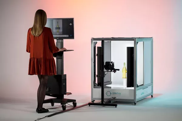 Kvinde betjener en automatiseret fotostation til produktfotografering