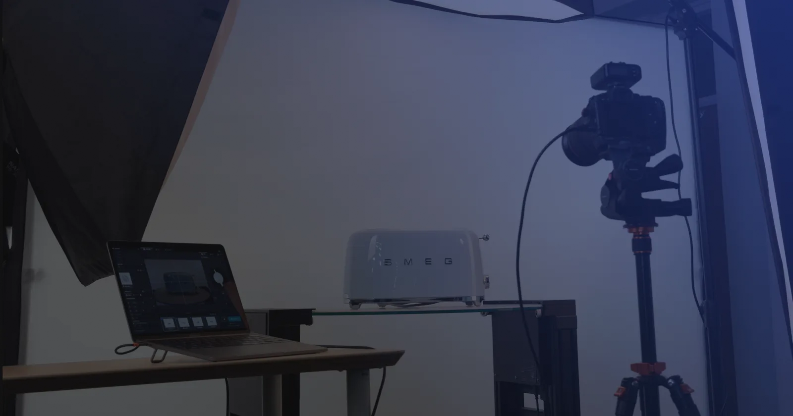 Tethered produktfotografering - en laptop med optagesoftware ved siden af et kamera på stativ og et produkt på en glashylde