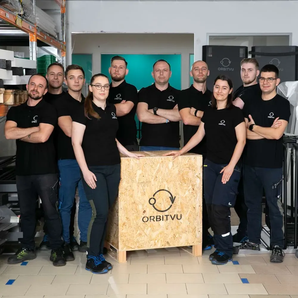 Orbitvus produktions- og logistikteam poserer med en trækasse med logo