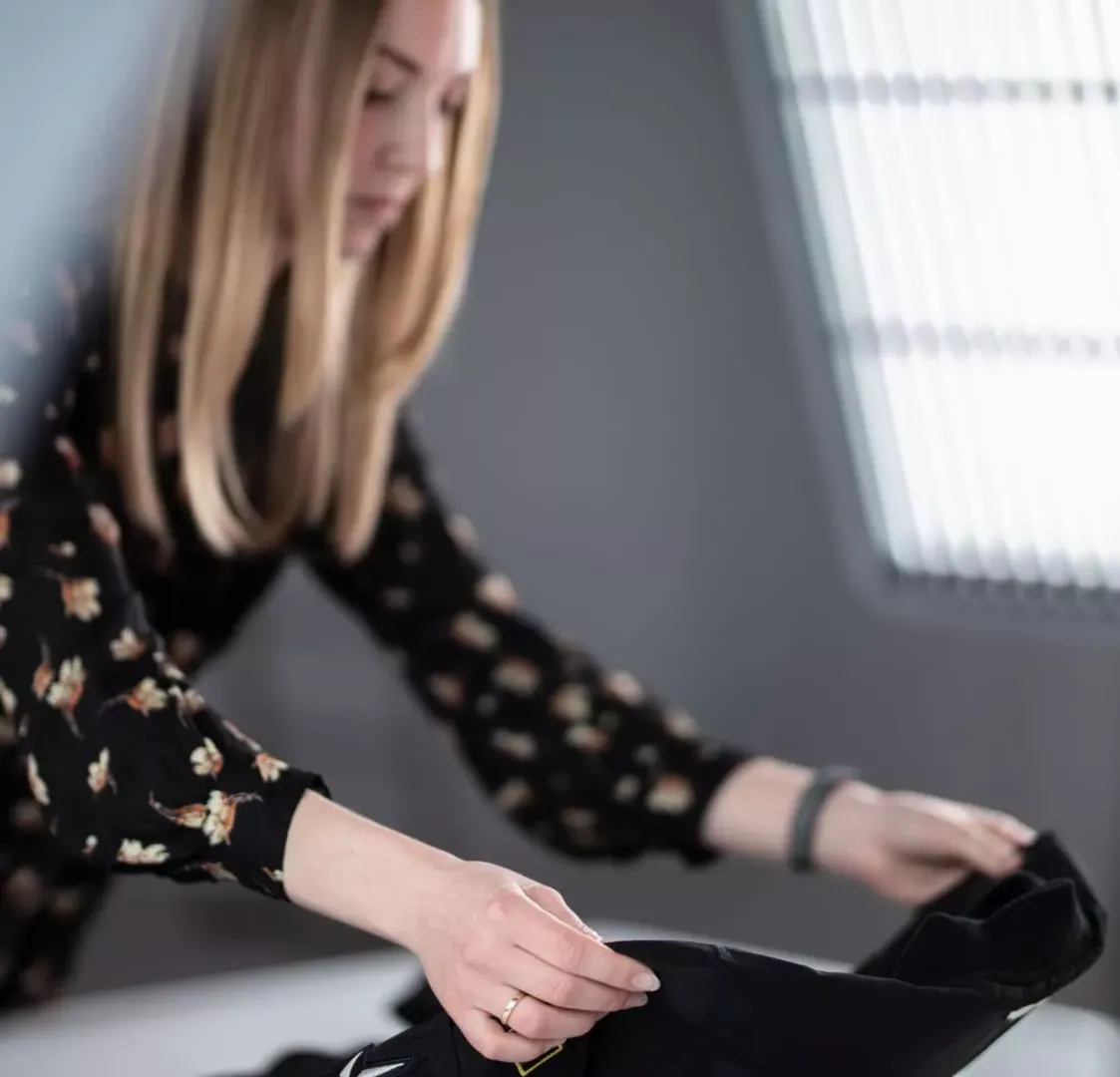 Produktstylist arrangerer sort beklædning til flat lay-fotografering